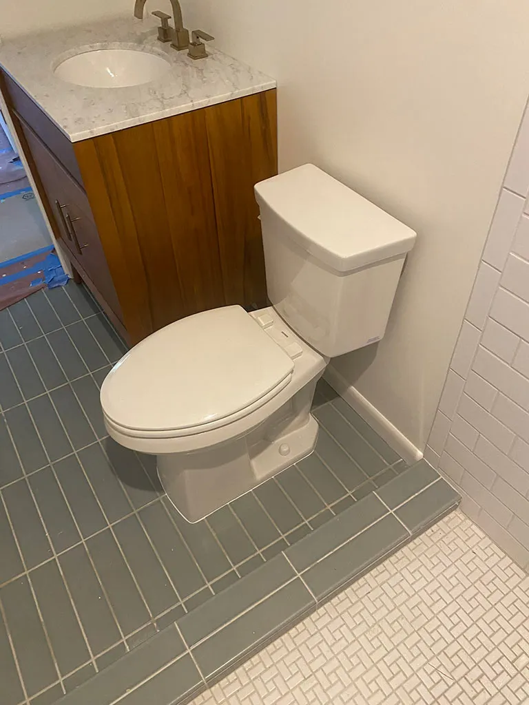 New toilet installed beside a stone-top vanity