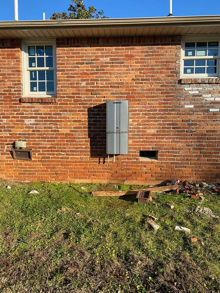 Tankless water heater cover on the side of a brick home