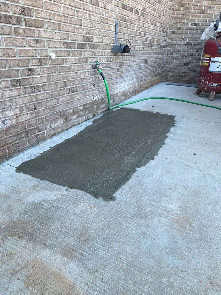 Concrete patched outside a brick home after a line repair