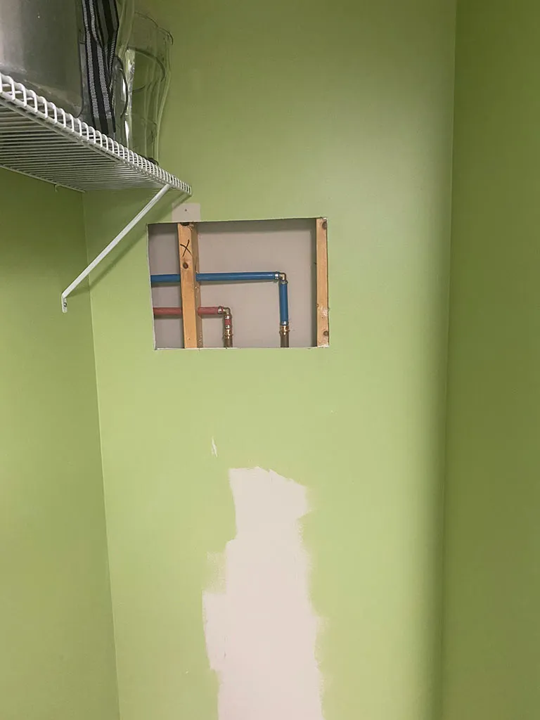 Access panel in a wall showing new water lines